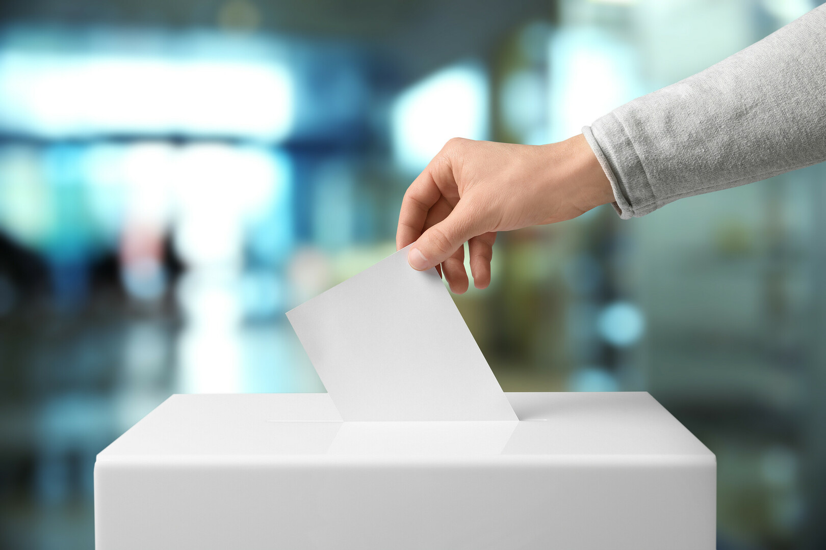 Hand placing a ballot into a ballot box